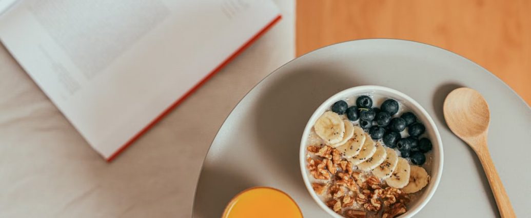 Top view of healthy breakfast with oatmeal, fresh fruit, and orange juice on a tray.